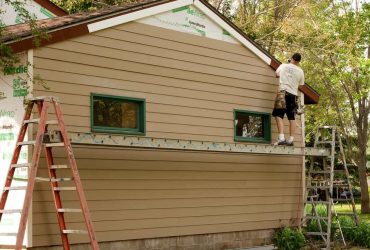 Installing-wooden-siding-for-a-house-with-green-framed-windows